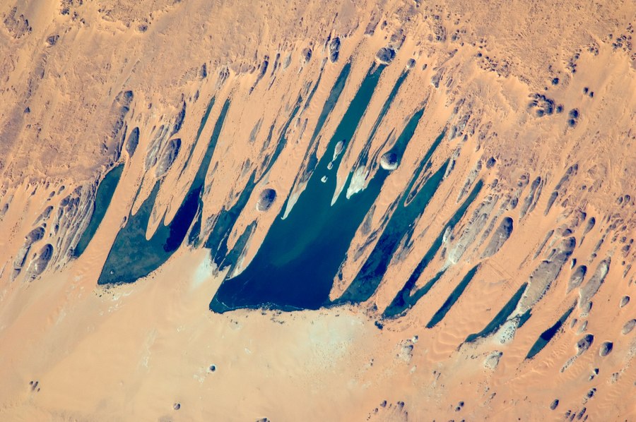 Jeziora Ounianga Serir i wkraczające do nich wydmy, widziane z Międzynarodowej Stacji Kosmicznej. (źródło: Wikipedia).